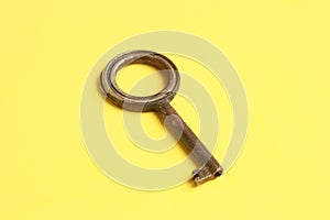 Top view of an old rusty key isolated on a yellow background