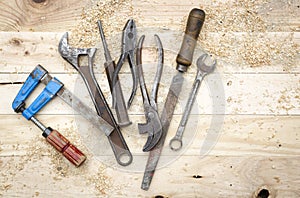 Top view of old and rusty toolset on natural pine wood workbench