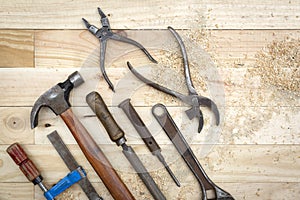 Top view of old and rusty toolset on natural pine wood workbench