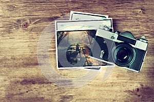 Top view of old vintage camera and pictures over wooden brown background