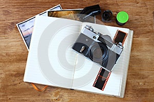 Top view of old vintage camera and pictures over wooden brown background.