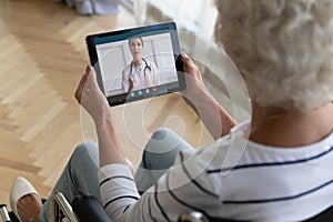 Top view older woman sitting in wheelchair, using computer tablet