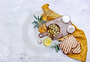 Top view Olive oil, green Olives, garlic and toast bread on a table,