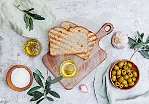Top view olive oil, olives, toast bread and leaves on white background,