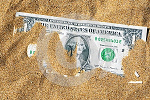 Top view of one dollar banknote buried in the sand. Closeup of dollar bill in the sand