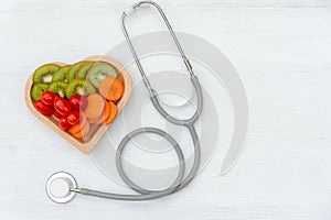 Top view. One single alone red heart love shape with bandage MD medical doctor physician`s stethoscope with vegetable healthy on