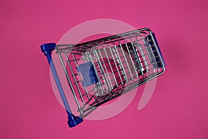 Top view on one single isolated shopping cart, purple magenta background