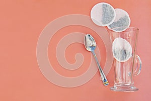 Top view of one tea bag and empty glass cup isolated on pink.