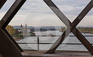 Top view onto the river Rhine with cargo ships through the steel girders of a crossing railway bridge