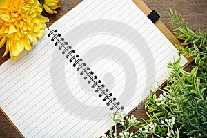 Top view of open blank notebook with flowers on Wood Background.