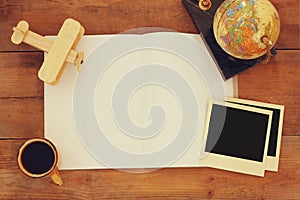 Top view of open blank notebook and and polaroid blank photography frames next to cup of coffee over wooden table. ready for