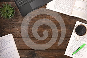 Top view of an open books with laptop, cup of coffee and home plant on a wooden background