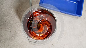 Top view of an open can of primer. Orange primer in a jar.