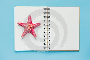 Top view of open empty notebook with starfish on pastel blue colorful background. Travel and holiday concept