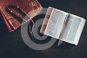 top view of open holy bible with rosary on table