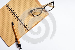 Top view of open notebook with pen or pencil and glasses isolated on white background. Flat lay, copy space