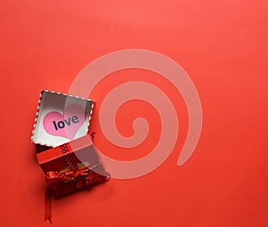 Top view of open red giftbox with love heart on the box in red background - valentine, birthday, anniversary