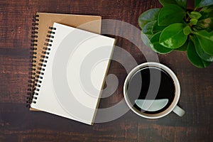 Top view of open school notebook with blank pages, Plant and Coffee cup on wooden table background.