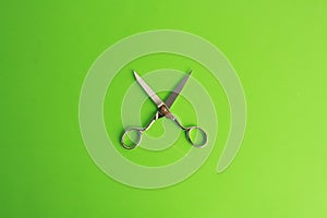 Top view of open sewing scissors on a green bckground
