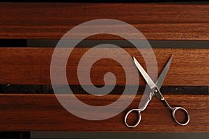 Top view of open sewing scissors on a wooden background