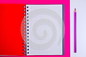 Top view of open spiral blank notebook with pencil on red desk background
