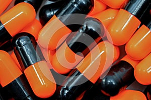 Top view of orange, black, capsule pills