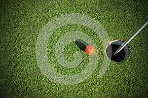 Top View of Orange Golf Ball near the Hole on Green