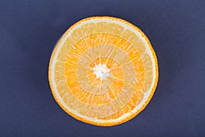 A top view of an organic half of orange on a dark purple background. Healthful and fresh citrus fruits.