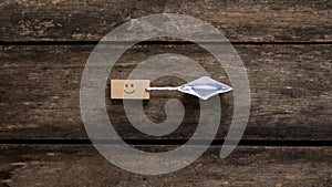 Top view of an origami paper boat pulling a wooden peg with a smiling face icon on it