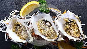 Top View of Oysters in Shells with Lemon on Black Textured Slate Background