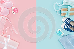 Top view of pacifiers, gifts, hat, booties, sneakers, bonnets on pink and blue background.