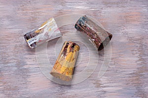 Top view of a paint brush glass containers covered in colorful brush strokes against a textured wall