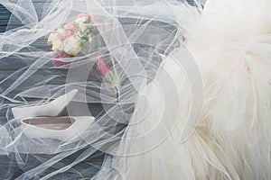 top view of pair of shoes, wedding dress and bouquet on wooden dark