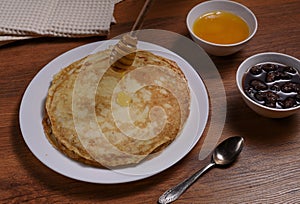 Top view of pancakes on white dish and honey jar