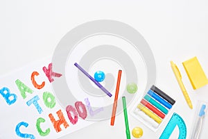 Top view of paper with back to school text near colorful felt-tip pens and highlighters isolated on white.