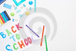 Top view of paper with back to school text near colorful felt-tip pens and school supplies isolated on white.