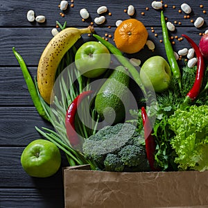 Top view paper bag of different fresh health food on white wooden background