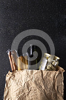 Top view of paper pack full of different kinds of cheese and bottle of olive oil on the dark table.Empty space