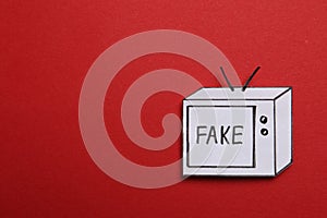 Top view of paper TV with word Fake on red background, space for text. Information warfare concept