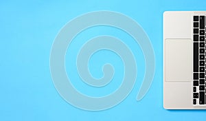 Top view of a part of a laptop keyboard on a blue background.