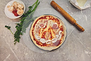 Top view on a partially cooked pizza with laid out products in the form of a smile