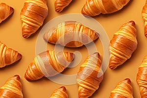 Top view pattern of freshly baked crispy croissants on a vibrant yellow-orange background