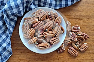 Top view of Pecan Nuts with a white bowl with a blue and white teatowel