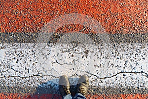 top view of the pedestrian crossing road markings and feet, red and white lines on the asphalt as a background