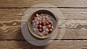 TOP VIEW: Peeled hazelnuts fill wooden cup on a wooden table