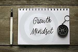 Top view of pen,compass and notebook written with Growth Mindset on wooden background