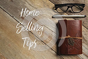 Top view of pen,glasses and notebook on wooden background written with Home Selling Tips. photo