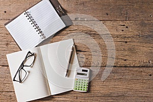 Top view of Pen, notebook, glasses, calculator,  smartphone on wooden table and copy space