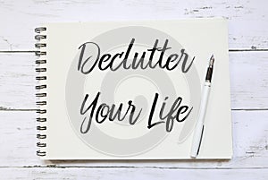 Top view of pen and notebook written with Declutter Your Life on wooden background.
