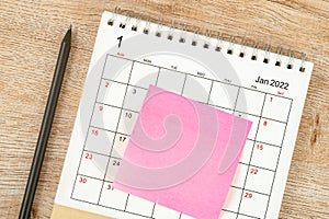 Top view of pencil, calendar planning and deadline with sticky note on wooden background, Calendar desk 2022 on January month